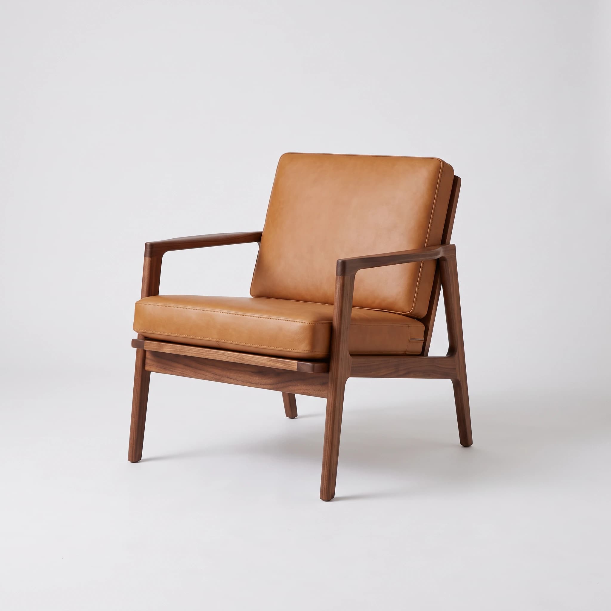 Walnut lounge chair with tan leather cushions on a seamless light grey studio background.